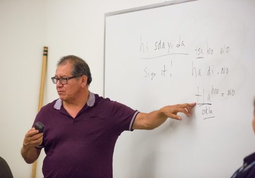Gil Jackson pointing a white board, teaching a Cherokee language class
